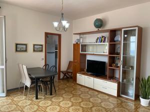 sala de estar con mesa de comedor y TV en Delizioso Bilocale ad Albenga con Terrazzo Vista Mare, en Albenga
