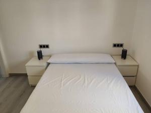 a white bed in a room with two dressers at CHARMING APARTMENT IN CALDETES in Caldes d'Estrac