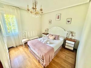 a bedroom with a white bed and a chandelier at La Casa de la Buganvilla in Gijón