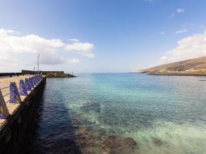 a body of water with blue chairs on a pier at Live Puertito Rifrajo in Puertito de Güímar