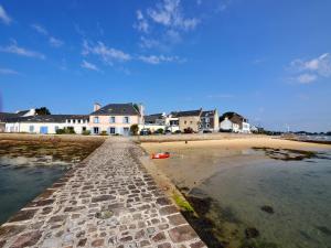 einen Strand mit Häusern und dem Wasser und einer Straße in der Unterkunft Emplacement de rêve, Maison à 20m des Plage in Plouhinec