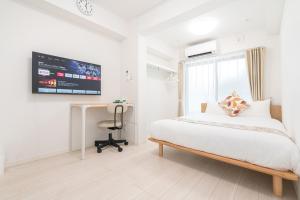 a bedroom with a bed and a desk and a monitor at リアル大久保　Apartment Hotel in Tokyo