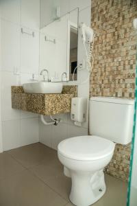 ein Badezimmer mit einem weißen WC und einem Waschbecken in der Unterkunft HN-Hotel Natal Penha in Penha
