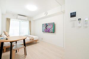 a white room with a bed and a table and a desk at リアル大久保　Apartment Hotel in Tokyo