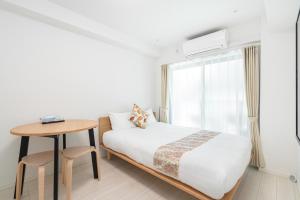 a bedroom with a bed and a table and a window at リアル大久保　Apartment Hotel in Tokyo