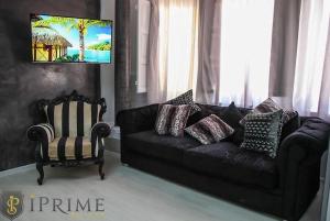 a living room with a black couch and a chair at Sliema Central Iprime Suites in Sliema