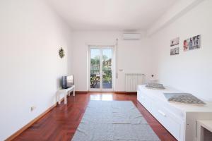 sala de estar con paredes blancas y suelo de madera. en Central House, en Lido di Ostia
