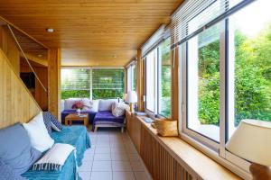 um alpendre com um sofá e janelas em Le Huic - Maison pour 9 avec jardin proche plage em Bénodet