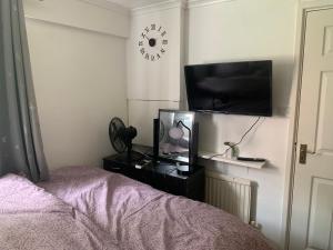 1 dormitorio con 1 cama, TV y reloj en Lovely room in South London en Addington