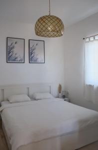 1 dormitorio blanco con 1 cama y 2 cuadros en la pared en Apartment Elena, en Sumartin