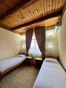 a room with two beds and a window in it at Hotel Caravan Serail in Samarkand