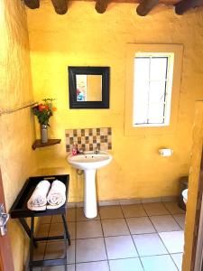 a yellow bathroom with a sink and a window at Majuli River House in Marloth Park