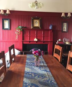 a dining room with a wooden table with flowers on it at Y Bwthyn Bach - Taff Trail in Treharris