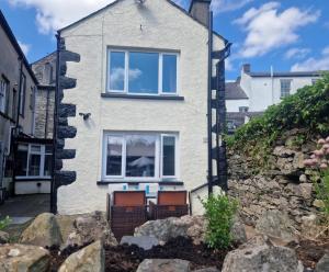 a house with two chairs in front of it at Courtyard Cottage in Cartmel