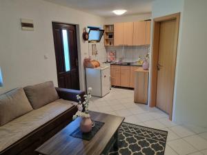 ein Wohnzimmer mit einem Sofa und einem Tisch sowie eine Küche in der Unterkunft Private beach holiday home Ilan in Kulen Vakuf