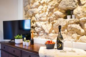 einen Fernseher auf dem Tisch mit einer Flasche Wein und Gläsern in der Unterkunft Il Vicoletto in Marostica