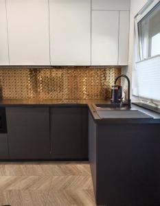 a kitchen with black and white cabinets and a sink at Apartament Nowy Władek 3 in Władysławowo +10 photos