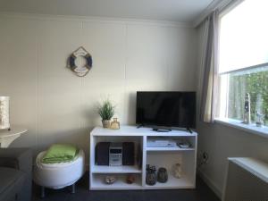 Egelantierlaan 21a في كادزاند: غرفة معيشة مع تلفزيون على خزانة بيضاء