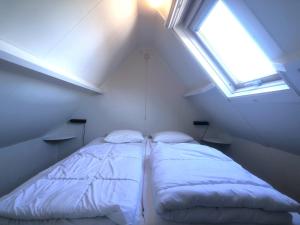 een bed in een kleine kamer met een raam bij Egelantierlaan 21a in Cadzand