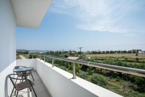 a balcony with two chairs and a view of a field at VOULA APARTMENTS in Faliraki