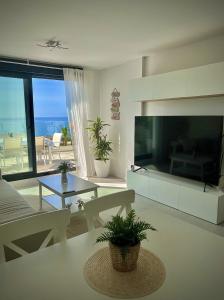 a living room with a large television and a living room with the ocean at Rincón Idilia (Málaga). in Rincón de la Victoria