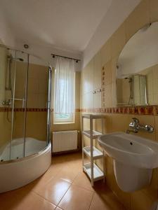 La salle de bains est pourvue d'une baignoire, d'un lavabo et d'une douche. dans l'établissement Pokoje gościnne u Małgosi, à Jarosławiec