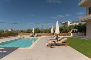 a swimming pool with lounge chairs and umbrellas at Oliva Verde in Galatás