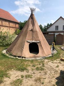 a teepee tent with a dog standing next to it at Kuckunniwi Tipidorf in Werder