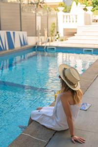 Juliana Hotel Cannes في كان: امرأة ترتدي قبعة جالسة بجوار حمام السباحة