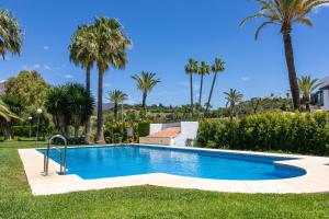 エステポナにあるSpacious Beachfront Town House in Estepona with Fully Equipped Kitchen, Pools, Garden, Sea Viewのヤシの木が茂る庭のスイミングプール