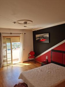1 dormitorio con 1 cama y 1 silla roja en Serra e Mar Ferragudo, en Ferragudo