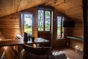 Cabaña de madera con mesa y ventanas de madera en Wooden tiny house Glamping cabin with hot tub 1, en Tuxford