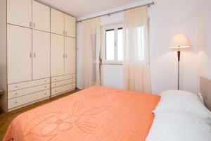 a bedroom with a bed with an orange blanket at Apartments Maria in Povlja