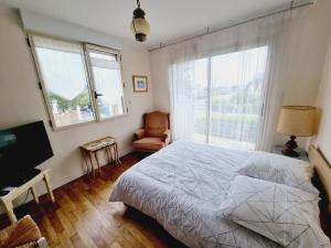 1 dormitorio con 1 cama, 1 silla y ventanas en Villa les mouettes, au bord de la mer., en Saint-Malo