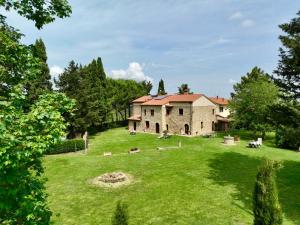 a large house on a grassy hill with cows in the yard at Agriturismo L'Antica Quercia in Pomarance