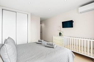 a white bedroom with a bed and a tv at Duplex Ocean View Apartment in Neptuno in Puerto de Santiago