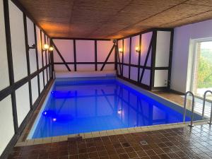 an indoor swimming pool with blue water in a building at Traumhaus am Wald 2 in Daun