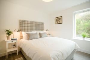 a white bedroom with a white bed and a window at Tomdhu Lodge - Seasgair Lodges in Boat of Garten