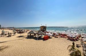 - une plage avec des parasols et des personnes sur la plage dans l'établissement Eliezer Ben Yehuda Residence WITH SHELTER, à Tel Aviv