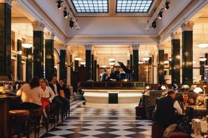 a crowd of people sitting in a restaurant with a piano at The Ned in London