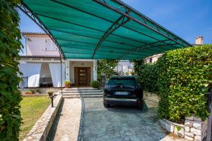 a car parked under a green canopy in a driveway at ARIA Sea View Apartment in Malinska