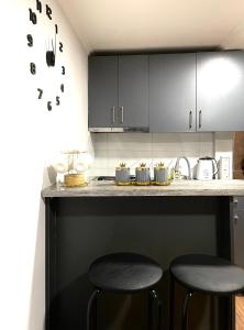 a kitchen with black cabinets and two stools at a counter at View Corner in Tbilisi City