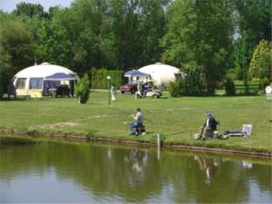 a group of people fishing in a park next to a river at Iglo Bungalow 17 in Chaam