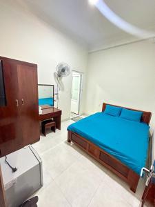 a bedroom with a blue bed and a desk at Guesthouse Thắng Linh in Da Lat