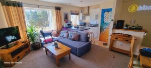 a living room with a blue couch and a kitchen at Harlech apartment Castle view in Harlech