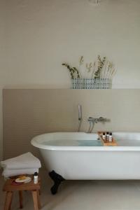 La salle de bains est pourvue d'une baignoire blanche et de plantes. dans l'établissement La Bastide du Mourre, à Oppède
