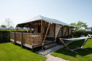 a yurt with a porch and a hammock in a yard at Glamping Kamperland in Kamperland