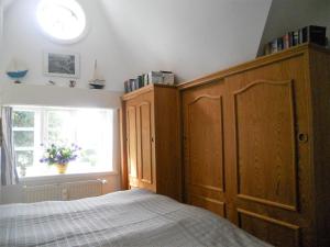a bedroom with a bed with a wooden cabinet and a window at Ole in Borgsum in Borgsum