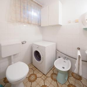 a white bathroom with a washing machine and a toilet at Apartments Maria in Povlja +12 photos