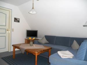 uma sala de estar com um sofá azul e uma mesa em Ole in Borgsum em Borgsum